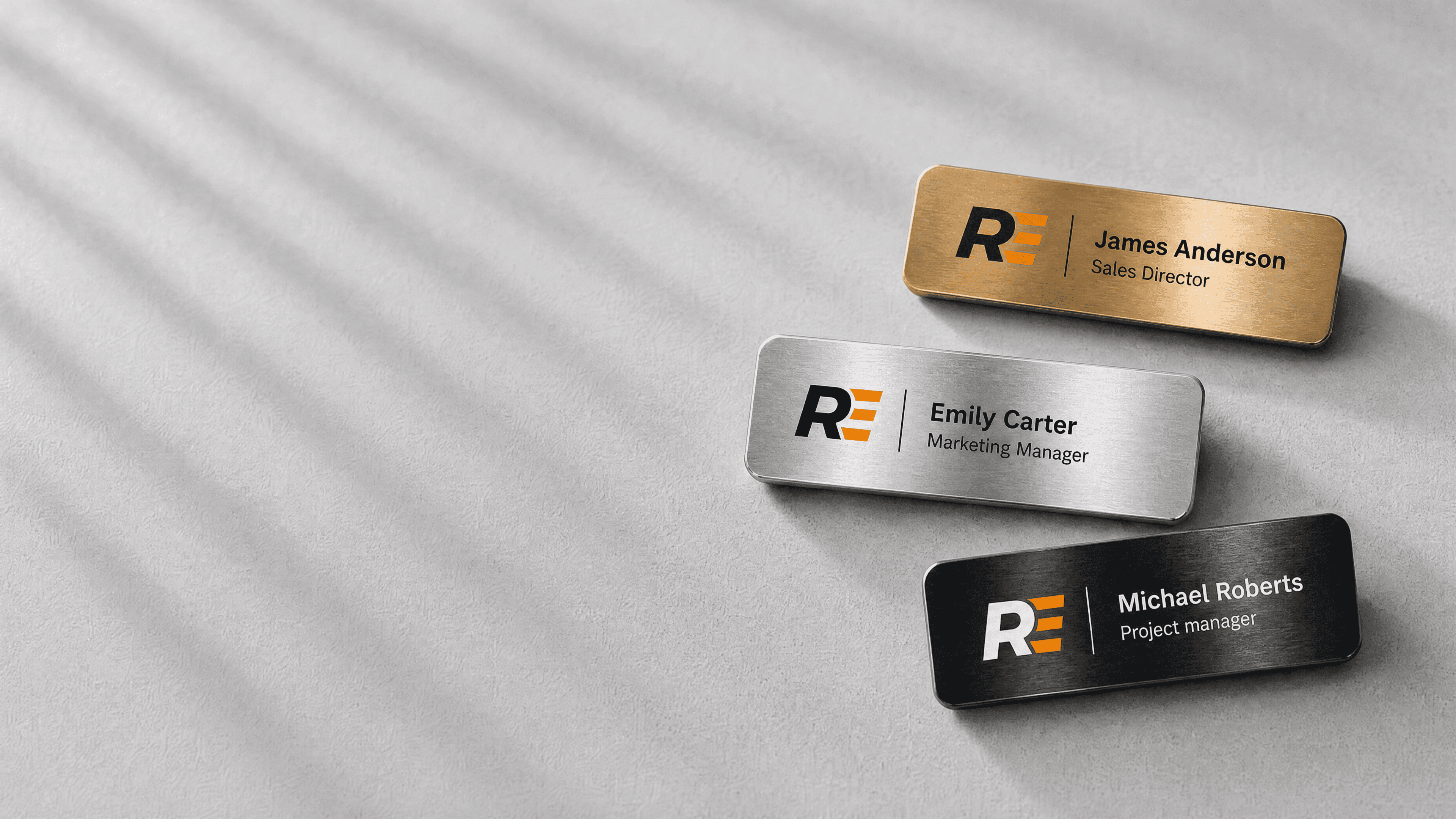 Drei Namensschilder aus gebürstetem Metall in Gold, Silber und Schwarz, personalisiert mit Logo, Name und Funktion, Recognition Express